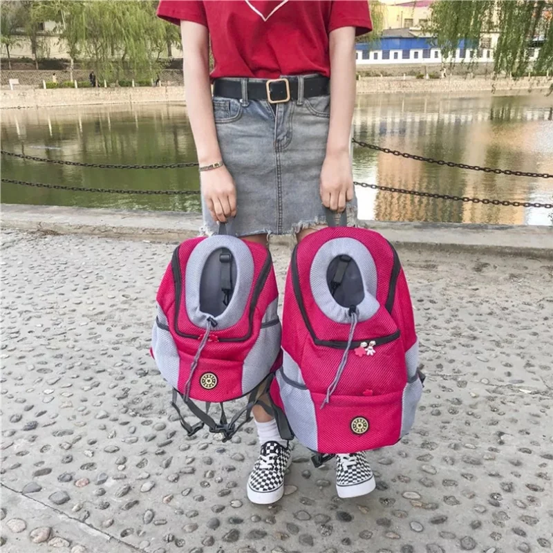 Portable Pet Backpack Carrier for small dogs in pink being held near a river.